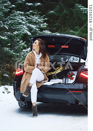 Tired driver woman stopped her car in winter forest to give herself rest and to drink a cup of coffee Tired driver woman stopped her car in winter forest to give herself rest and to drink a cup of coffee 85293201