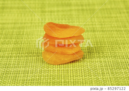 Dried apricots stacked on a green background Dried apricots stacked on a green background 85297122