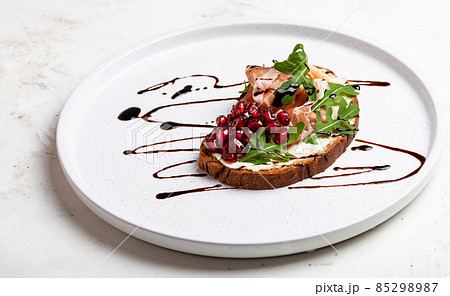 Sandwich with jamon and herbs and pomegranate on white plate close-up Sandwich with jamon and herbs and pomegranate on white plate close-up 85298987