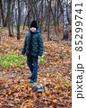 Looks into the distance. Autumn lighting, yellow autumn leaves all around. Autumn park forest. The boy is standing in the autumn park. 85299741