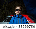 . Brutal view A boy in cool sunglasses stands at night against the backdrop of a car. Brutal view . High quality photo 85299750
