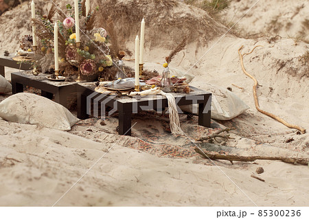 A table  designed for a boho style event with an eucalyptus, vintage plates and other rustic touches. On seaside in the sand dunes 85300236