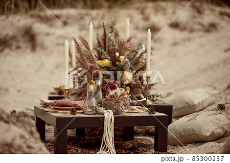 A table  designed for a boho style event with an eucalyptus, vintage plates and other rustic touches. On seaside in the sand dunes 85300237