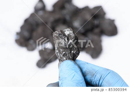 Coal lump in scientist hand. Laboratory coal analysis, fossil fuel research. 85300394