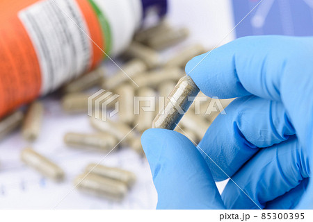 Supplement capsule in scientist hands, with bottle and pills on background. Supplement capsule in scientist hands, with bottle and pills on background. 85300395