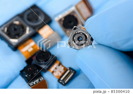 Smartphone camera module in researcher hand, with other cell phone camera sensors in other. Smartphone camera module in researcher hand, with other cell phone camera sensors in other. 85300410