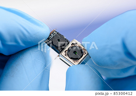 Two cell phone camera modules in scientist hands. 85300412