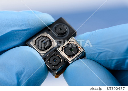 Smartphone camera modules in scientist hands. Different sensor sizes and technology used. 85300427