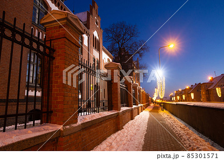 Klaipeda, Lithuania - 01 15 21: Old historical Neo-Gothic University building campus in winter snow, pink sunset colors and city lights. A fairytale atmospheric photo for postcards, touristic booklets Klaipeda, Lithuania - 01 15 21: Old historical Neo-Gothic University building campus in winter snow, pink sunset colors and city lights. A fairytale atmospheric photo for postcards, touristic booklets 85301571