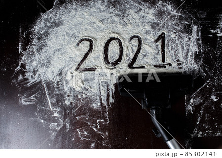 Abstract background of a photo of the outgoing year 2021. Drawing from flour, the vacuum cleaner removes the figures of the outgoing year. top view Abstract background of a photo of the outgoing year 2021. Drawing from flour, the vacuum cleaner removes the figures of the outgoing year. top view 85302141