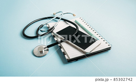 Telemedicine or telehealth virtual visit, video visit, remote doctor video chat consultation concept with smartphone, open notepad and stethoscope on blue background Telemedicine or telehealth virtual visit, video visit, remote doctor video chat consultation concept with smartphone, open notepad and stethoscope on blue background 85302742