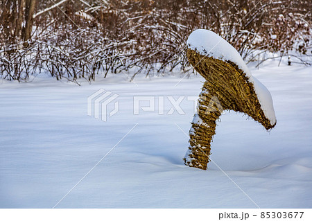 Garden installation in the form of a mushroom made of straw in the snow 85303677