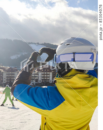 smiling woman in ski outfit making heart love symbol of hands smiling woman in ski outfit making heart love symbol of hands 85304076