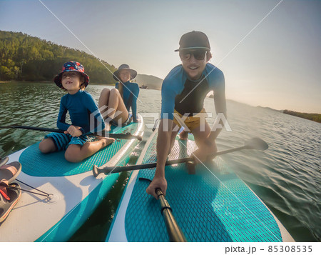happy family of three, dad, mom and son, enjoying stand up paddling during summer vacation 85308535
