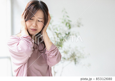 部屋着を着て頭を抱える体調不良の女性 85312680
