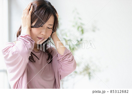 部屋着を着て頭を抱える体調不良の女性 85312682
