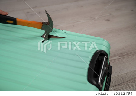 A woman hits a suitcase with a hammer on a white background. 85312794