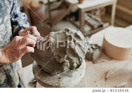 Close-up of potter using pottery wheel to make ceramic sculpture, he making features of the human face 85316436