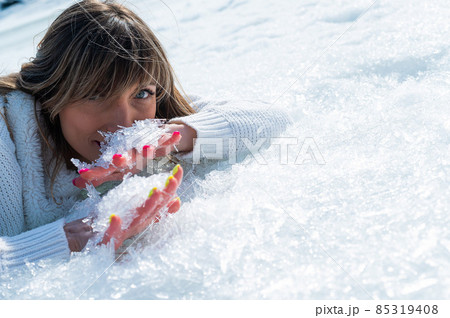 Close-up portrait of a caucasian woman lying on the snow.  85319408