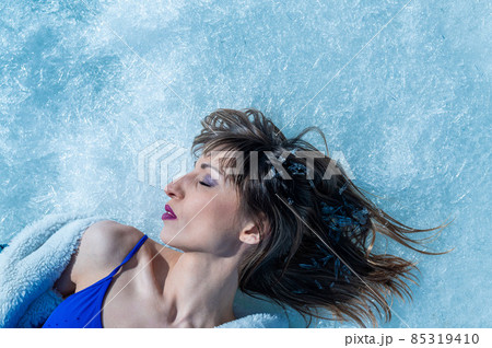 Close-up portrait of a caucasian woman lying on the snow.  85319410