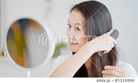 髪にブラシをかけるシニア女性 85319990