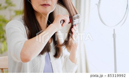 髪にブラシをかけるシニア女性 85319992