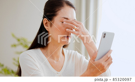 スマートフォンを見る眼精疲労のシニア女性 スマートフォンを見る眼精疲労のシニア女性 85320097
