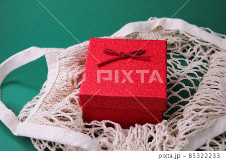 a red gift box in an eco-friendly bag on a green background. a red gift box in an eco-friendly bag on a green background. 85322233