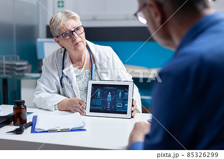 Physician explaining human body analysis on tablet to patient with disease Physician explaining human body analysis on tablet to patient with disease 85326299