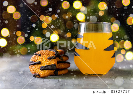 orange mandarin cocktail in glass with black stripes and cookies. Christmas holiday drink. Concept for children new year orange mandarin cocktail in glass with black stripes and cookies. Christmas holiday drink. Concept for children new year 85327717