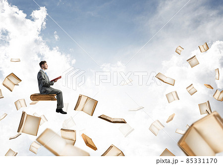 Man reading book and many of them flying in air Man reading book and many of them flying in air 85331170