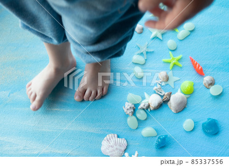 baby feet on Seashells summer background. Many different seashells, starfish on a background of blue paint strokes. Place for text. 85337556