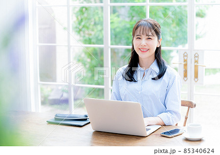 メインビジュアルにも パソコンの仕事をしながらカメラ目線の美しい女性 前ボケとコピースペースあり メインビジュアルにも パソコンの仕事をしながらカメラ目線の美しい女性 前ボケとコピースペースあり 85340624