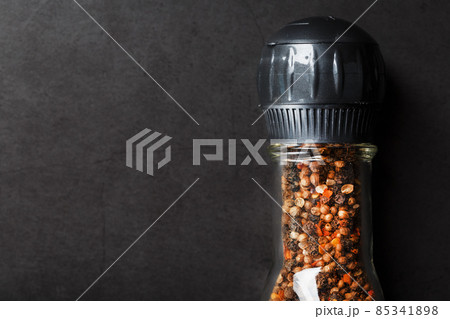 A mixture of seasonings, spices and herbs in a glass mill on a black background. 85341898