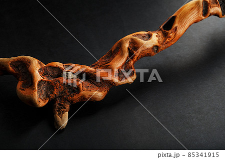 Textured curved Wooden snag of brown color with texture on a black background with free space. 85341915