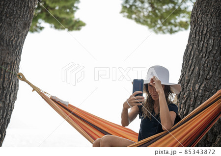 Young brunette making selfies while sitting in a hammock 85343872