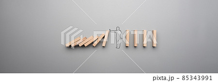 Wide cropped image of the outline of a businessman stopping the domino Wide cropped image of the outline of a businessman stopping the domino 85343991