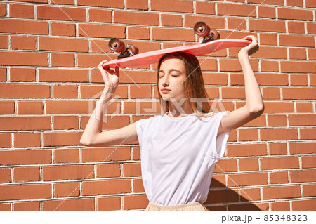 Girl with skateboard. Town landscape. Black sneakers. New normal travel Girl with skateboard. Town landscape. Black sneakers. New normal travel 85348323