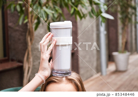 Pretty girl drink beverage outdoors. Buy takeaway coffee in own cup. Real people Pretty girl drink beverage outdoors. Buy takeaway coffee in own cup. Real people 85348446