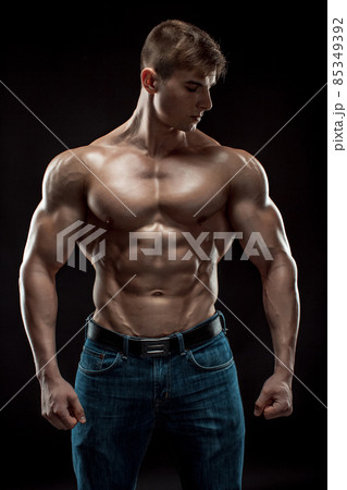 Muscular bodybuilder guy doing posing over black background Muscular bodybuilder guy doing posing over black background 85349392