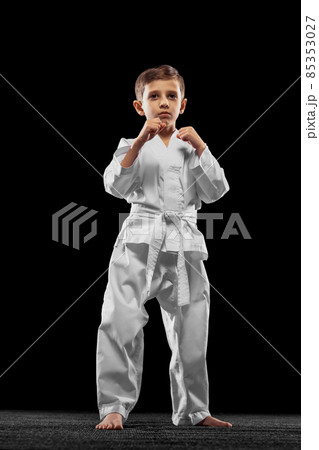 One little kid, boy, taekwondo athlete wearing white dobok isolated over dark background. Concept of sport, education, skills 85353027