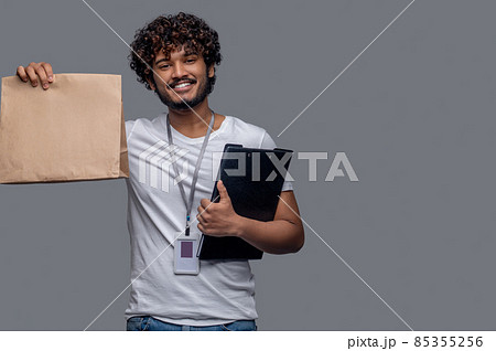 Contented delivery person with a paper bag looking ahead 85355256
