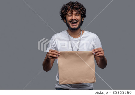 High-spirited deliveryman holding the package with both hands before him High-spirited deliveryman holding the package with both hands before him 85355260