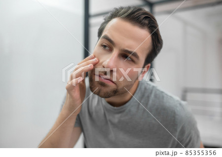 Man near the mirror scrutinizing himself Man near the mirror scrutinizing himself 85355356