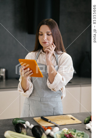 Young housewife looking for new cooking ideas on internet Young housewife looking for new cooking ideas on internet 85355666