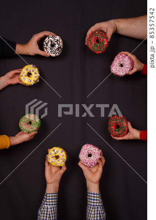 Set of holiday decorated donuts in hands on dark background 85357542