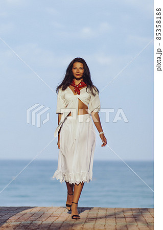 Woman in Elegant Beach Outfit Outdoors Against Sea Background During Summer Vacations 85358188