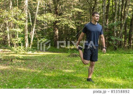 A man athlete runs in the park outdoors, around the forest, oak trees green grass young enduring athletic athlete sport workout jogger wellness jogging man. Adult energy cross, stretching stretches 85358892