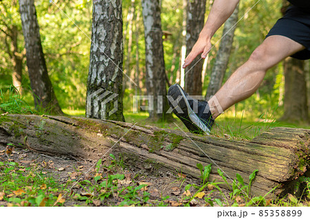 A young enduring athletic athlete is doing stretching in the forest outdoors, around the forest, oak trees.active forest, fitness young recreation motion, jogging wellbeing. Summer leisure runners 85358899