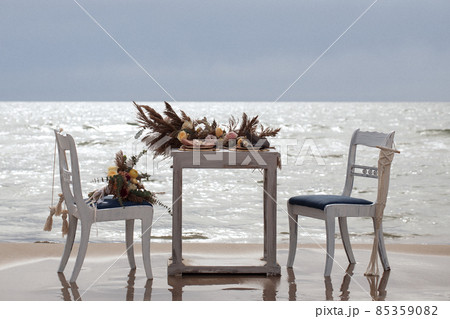 A table  designed for a boho style event with an eucalyptus, vintage plates and other rustic touches. On seaside in the sand 85359082